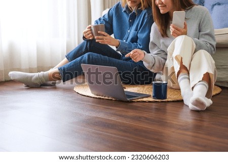 Closeup image of a young couple women using mobile phone and laptop computer together