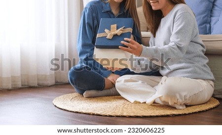 Closeup image of a young couple women opening a gift box together