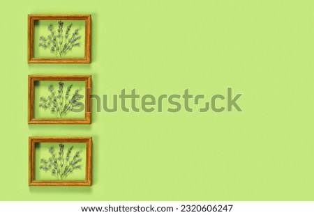 Wooden frames with  bouquet of fragrant lavender in  rustic style on green wall. Holiday party decoration. Vintage floral card. Interior concept.