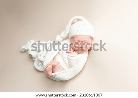 wrapped newborn baby boy on a light background. hat cap on the child. Studio shot of a newborn. Royalty-Free Stock Photo #2320611367