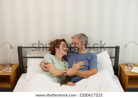 Mature couple relaxing in bed in the morning at home Royalty-Free Stock Photo #2320617223