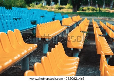 Empty rows of seats in the stadium. Blue and yellow chairs, nobody present at a sport show simple abstract concept. Chair rows up close, side view