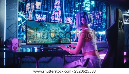 Young Female Gamer Playing Strategy Video Game with Modern Graphics on Her Computer. Stylish Futuristic Cyberpunk Gaming Neon Room with Cosplay Gamer Girl in Headphones. Photo from the Back