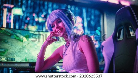 Portrait of a Beautiful Cyberpunk Cosplay Gamer with Blue Hair Looking at Camera with a Happy Smile. A Young, Excited Gamer Female in Futuristic Neon Room. Gaming and Streaming Concept Royalty-Free Stock Photo #2320625537