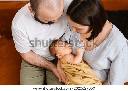 Top view of parents hold newborn infant, happy mother and father hold tony baby in arms at cozy home Royalty-Free Stock Photo #2320627069