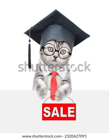 Happy graduated cat wearing eyeglasses and necktie looks above empty white banner and  holds signboard with labeled "sale". isolated on white background