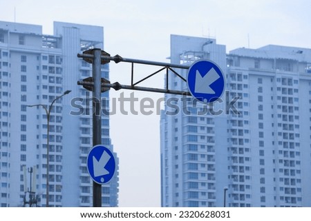Turn left and right,road sign,traffic sign in blue and white colour with building skyscraper
Turn left and right,road sign,traffic sign in blue and white colour with building skyscraper.