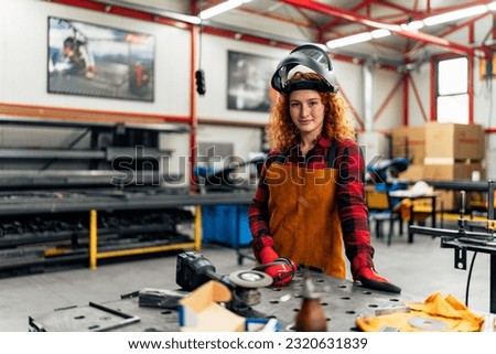A young woman poses in front of her workshop, the first generation business owner in her family
