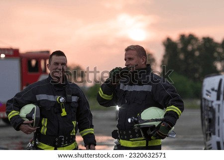 fireman using walkie talkie at rescue action fire truck and fireman's team in background. Royalty-Free Stock Photo #2320632571
