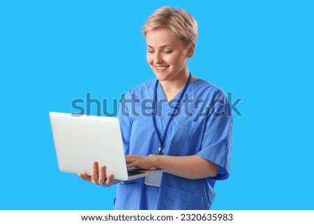 Female medical intern using laptop on blue background