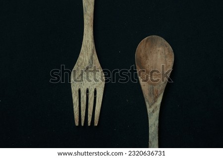It's a picture of a spoon and a fork made of wood with a black background