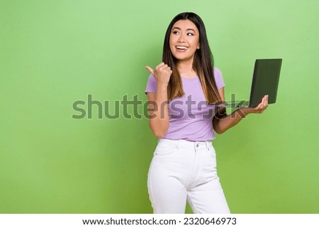 Photo of chinese young woman working use laptop directing finger empty space looking remote job offer isolated on green color background