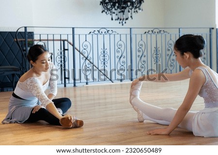 Ballerina girl doing flexible stretching with her teacher