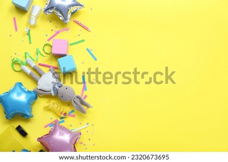 Baby toys with confetti and balloons on yellow background. Children's Day celebration