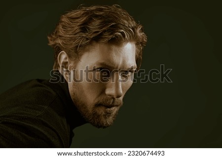 Art portrait in a dark key of a handsome forty-year-old man with curly hair, dressed in a black pullover, who looks directly and thoughtfully into the camera. Psychological picture. People, emotions.
