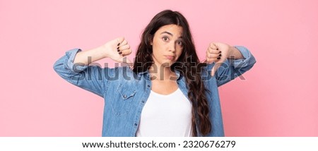 young pretty woman looking sad, disappointed or angry, showing thumbs down in disagreement, feeling frustrated Royalty-Free Stock Photo #2320676279
