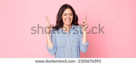 young pretty woman smiling and anxiously crossing both fingers, feeling worried and wishing or hoping for good luck Royalty-Free Stock Photo #2320676393