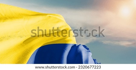 Colombia national flag cloth fabric waving on beautiful Cloudy Background.