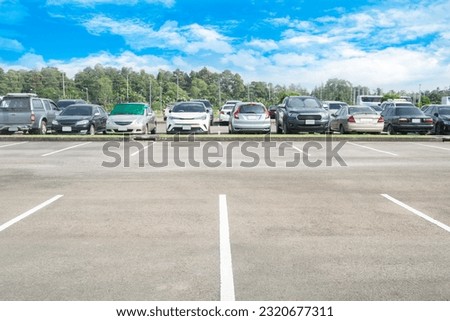 Wide empty asphalt parking lot background. with many cars parked background. outdoor empty space parking lot with trees and cloudy sky. outside parking lot in a park
