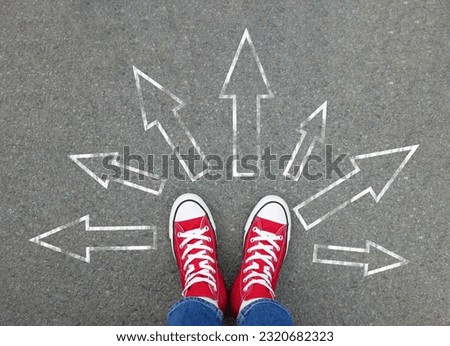 Choosing future profession. Girl standing in front of drawn signs on asphalt, top view. Arrows pointing in different directions as diversity of opportunities Royalty-Free Stock Photo #2320682323