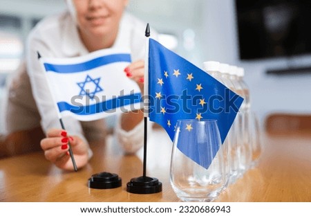 Employee of delegation prepares negotiating table - sets up the flag of European Union and Israel