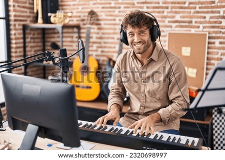 Young man musician playing piano keyboard at music studio Royalty-Free Stock Photo #2320698997