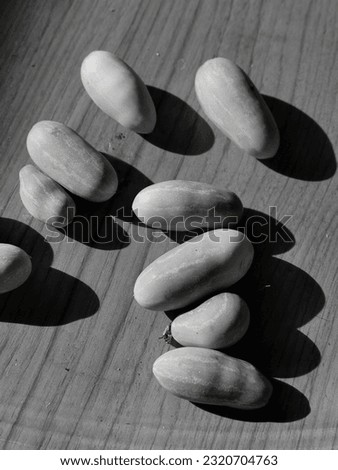 A black and white photograph of fruit lying on a table with the evening sun cast a long shadow.