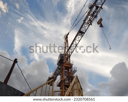 This is the front of the tower crane photographed from below, where you can see the cabin where the operator operates the crane, the hook block and some of the components of the tower crane. Royalty-Free Stock Photo #2320708561