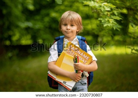 Cute preschool child, wearing school backpack, holding notebook and pencils for school, prepared for first day at school. SIGN ON THE BOOK: START READING AND WRITING