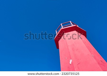 Red lighthouse isolated in blue sky