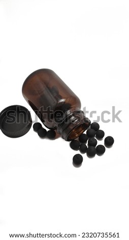 Round black herbal medicine pouring from black bottle isolated on white background. natural herbs, organic pills, vitamins from medicinal plants, calcium concept, antidepressants and painkillers