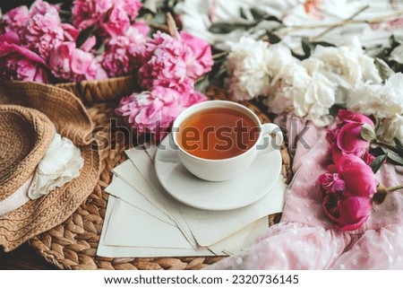 Beautiful spring composition, good morning concept. Cup of tea, peonies and open book.