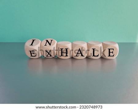 Inhale, Exhale concept. Turned a dice and changes the word INHALE to EXHALE. Beautiful blue background, grey table, copy space. Business and INHALE or EXHALE concept.