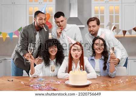 Happy friends with tasty cake celebrating birthday in kitchen