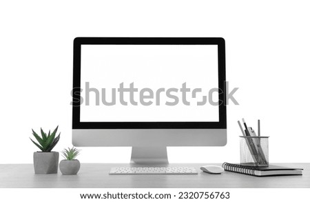 Computer, potted plants and stationery on table against white background. Stylish workplace