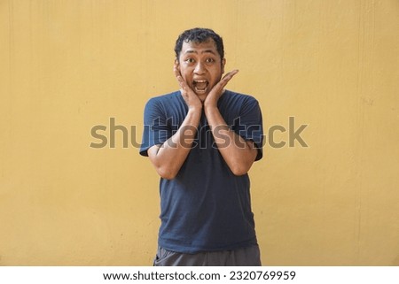 Asian man feel shocked, surprised and excited on yellow background