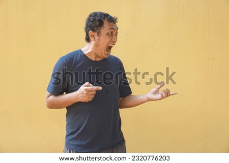 Asian man feel angry with show finger on yellow background. Side view situation