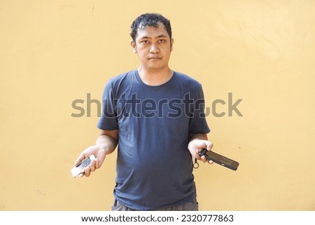 Asian man feel shocked, surprised, confuse and excited while holding his smartphone on yellow background