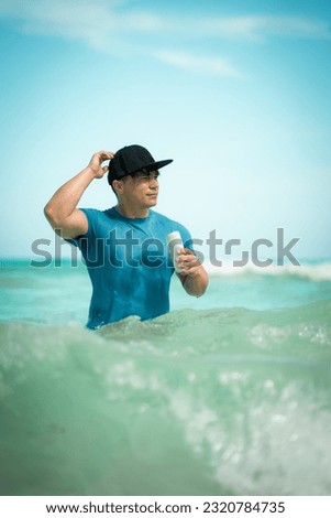 A caucasian man at Cancun beach. Blue color photography. Young man enjoying Cancun sea on a sunny day while holding a bear can.