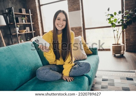 Full size portrait of lovely positive lady sit sofa hold smart phone blogging enjoy pastime chilling house inside