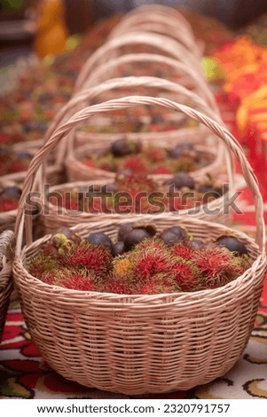 Red rambutan and mangosteen fruits in woven baskets.