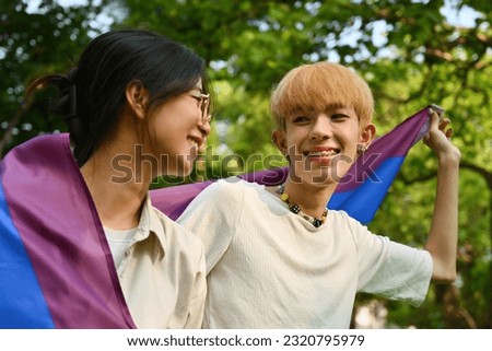 Celebration Pride month of LGBT concept with LGBT youth boy and girl holding a rainbow flag with outdoor background.