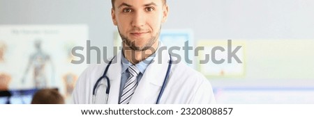 Portrait of smiling young doctor with a stethoscope on background of office in clinic. Royalty-Free Stock Photo #2320808857