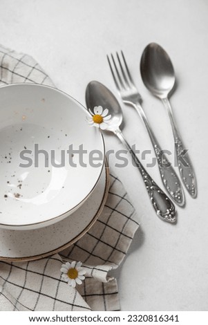 Plates with silver cutlery and napkin on grunge white background