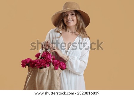 Beautiful young woman with eco bag and peony flowers on beige background