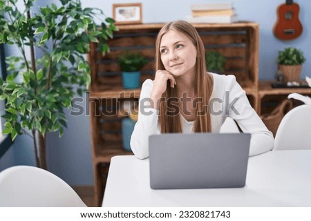 Young caucasian woman using laptop sitting on table at home
