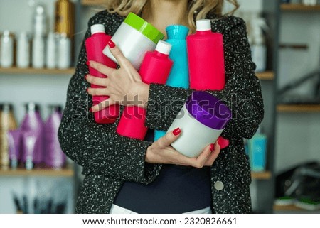 Lot of plastic bottles with cosmetics in female hands against background of shelves in store. Recycling plastic. Self care. Plastic wastes Royalty-Free Stock Photo #2320826661