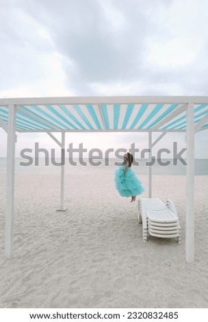 Little girl in mint dress is jumping on the beach