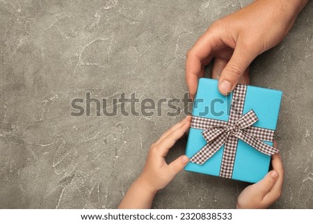 Father's day gift with daughter or son holding dad's hands giving present box to tell I love you dad, I am so thankful and happy fathers day. Top view