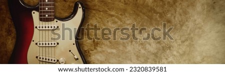 Popular electric guitars : Two tone rock and roll style red-black electric guitar leaning against old grunge vintage blank plaster background with copy space : selective focus.
